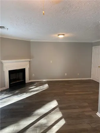 a view of an empty room with wooden floor and a fireplace
