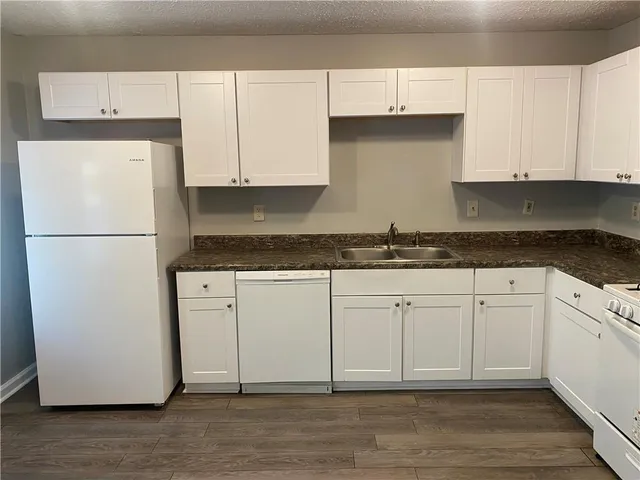 a kitchen with granite countertop white cabinets and a refrigerator