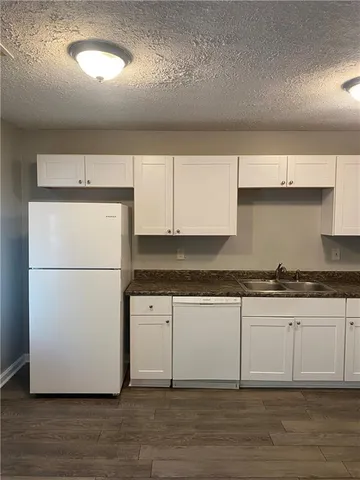 a kitchen with granite countertop a stove a refrigerator and a sink with wooden floors