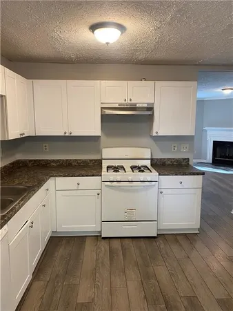 a kitchen with granite countertop white cabinets and white appliances