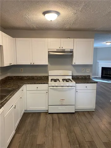 a kitchen with granite countertop white cabinets and white appliances