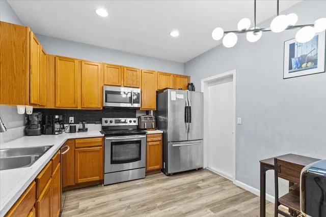 a kitchen with stainless steel appliances granite countertop a refrigerator a stove a sink and dishwasher with wooden floor