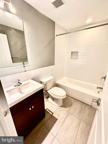 a bathroom with a bathtub shower sink vanity mirror and toilet