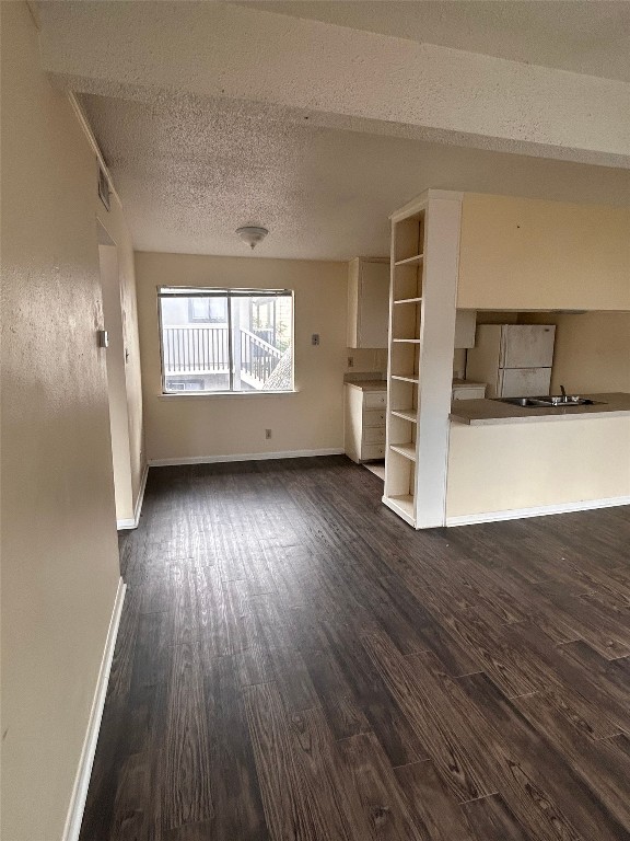 2408 Longview Street, Unit 202 Austin, TX 78705 - Photo 4 of 11 Unfurnished living room with a textured ceiling and dark wood-style floors
