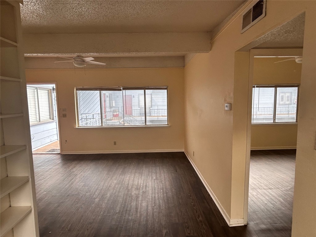 2408 Longview Street, Unit 202 Austin, TX 78705 - Photo 5 of 11 Empty room featuring ceiling fan, dark wood-style flooring, a textured ceiling, and plenty of natural light