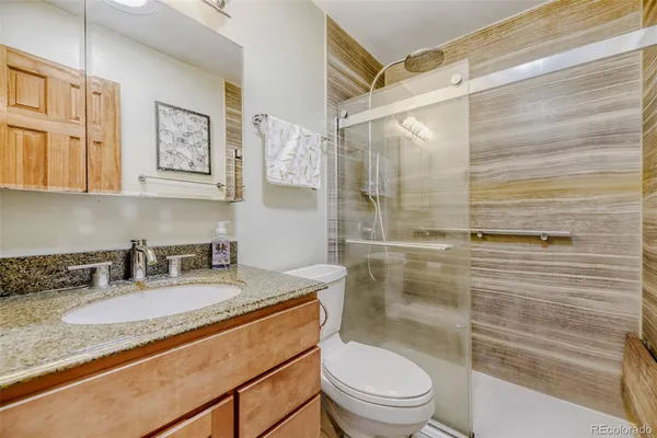 a bathroom with a granite countertop sink toilet a mirror and shower