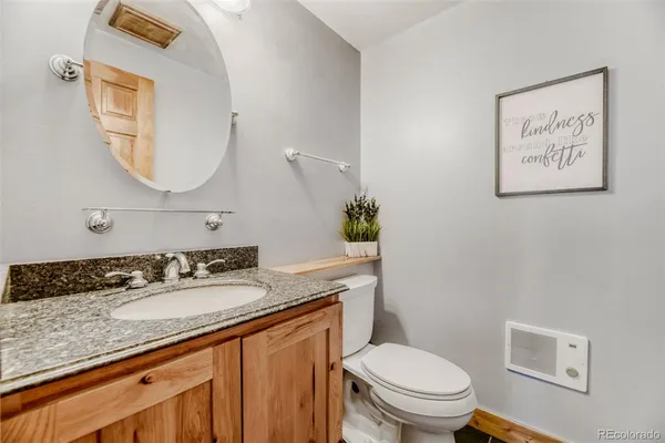 a bathroom with a granite countertop toilet a sink and a mirror