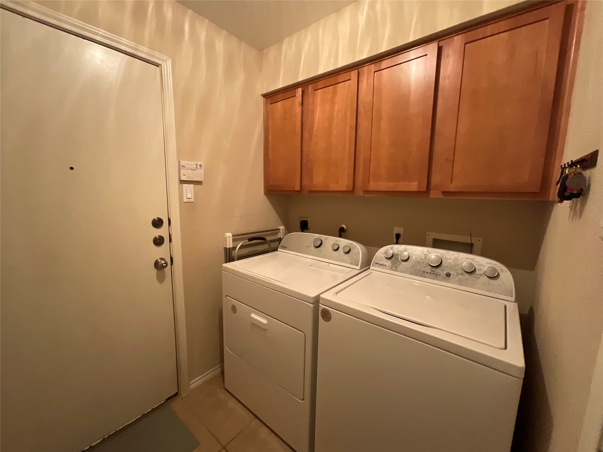 14013 Rountree Ranch Lane Austin, TX 78717 - Photo 16 of 19 Laundry room featuring cabinet space, light tile patterned floors, and washer and clothes dryer