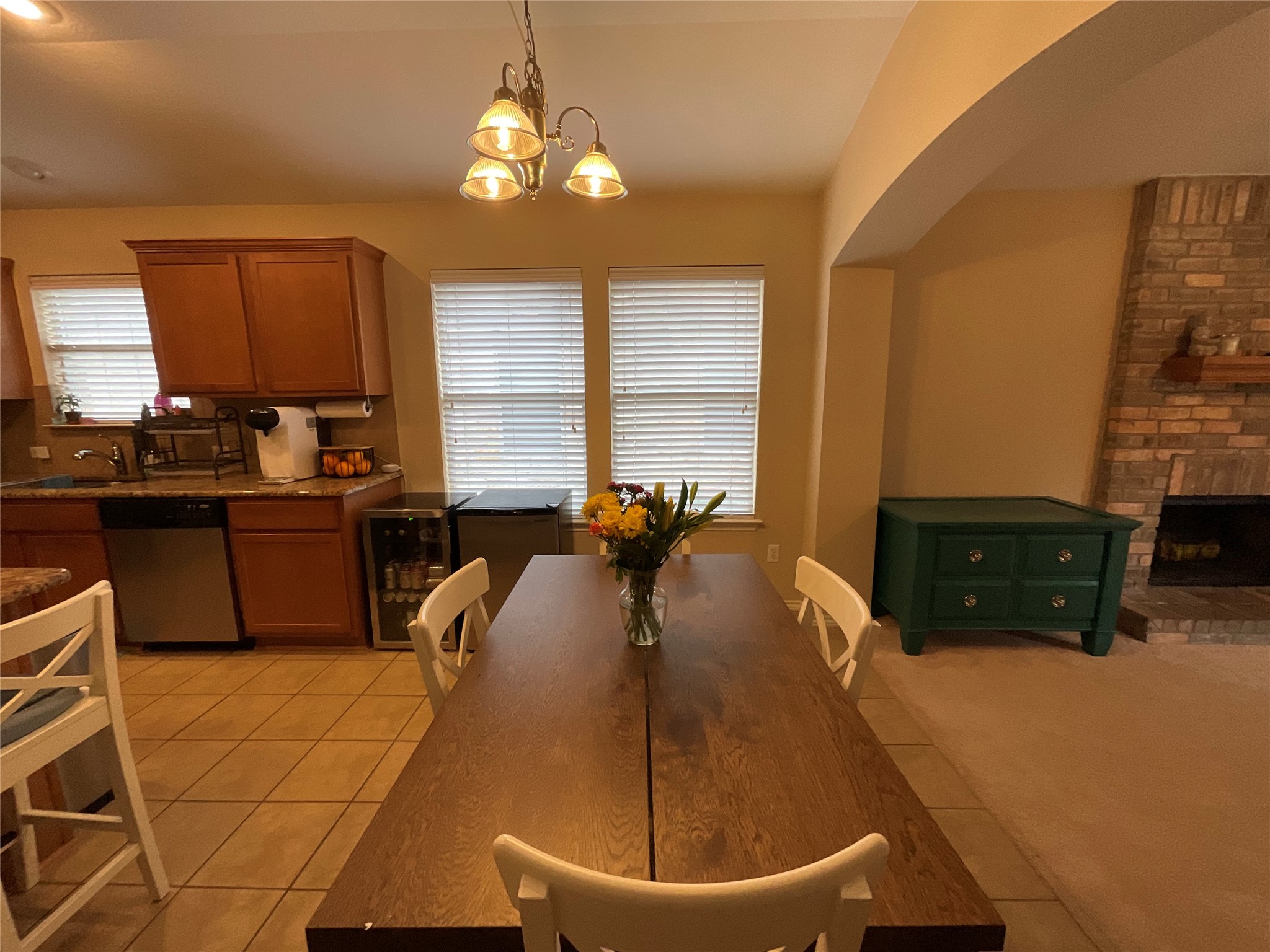14013 Rountree Ranch Lane Austin, TX 78717 - Photo 5 of 19 Dining area with a chandelier, a brick fireplace, light tile patterned flooring, and light colored carpet