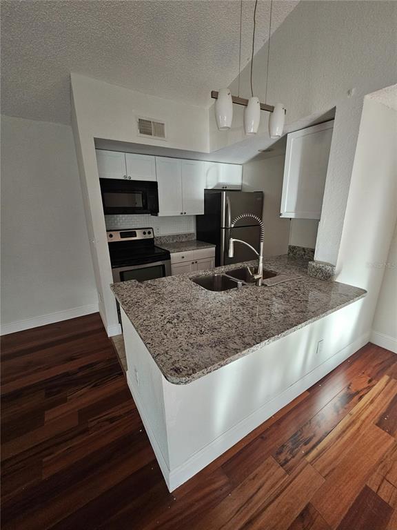 5132 Conroy Road, Unit 937 Orlando, FL 32811 - Photo 4 of 6 a kitchen with kitchen island granite countertop a sink stove and refrigerator