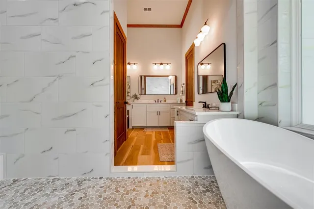 a bathroom with a tub a sink and a large mirror next to a window
