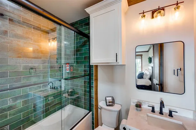 a bathroom with a granite countertop sink a toilet a mirror and shower