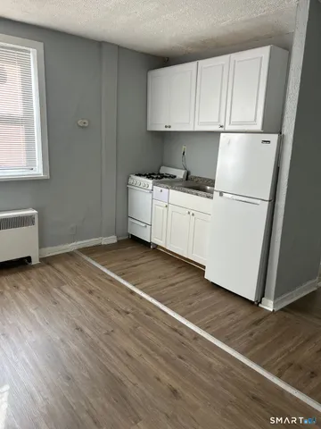 a room with wooden floor and white cabinets