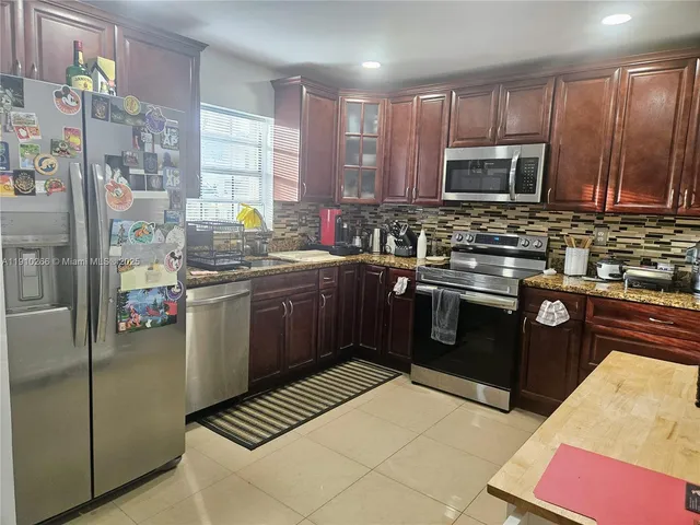 a kitchen with stainless steel appliances kitchen island granite countertop a stove a sink dishwasher and a refrigerator