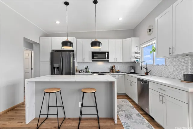 a kitchen with stainless steel appliances granite countertop a sink a stove a refrigerator and white cabinets with wooden floor