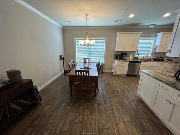 a kitchen with stainless steel appliances granite countertop wooden floors stove top oven and chairs