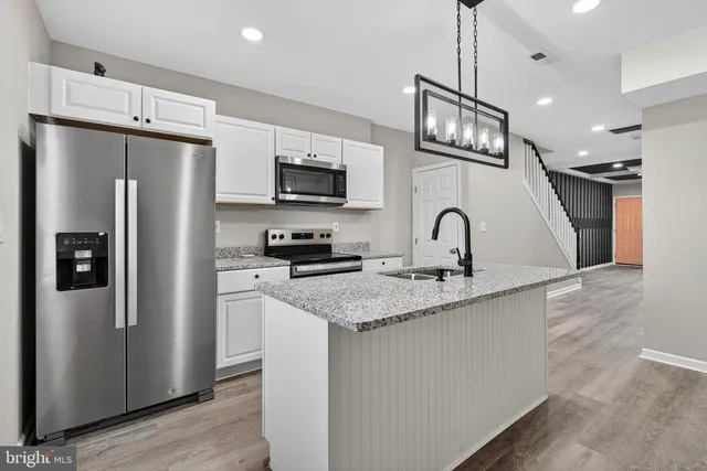 a kitchen with stainless steel appliances granite countertop a refrigerator a sink a stove a microwave and island