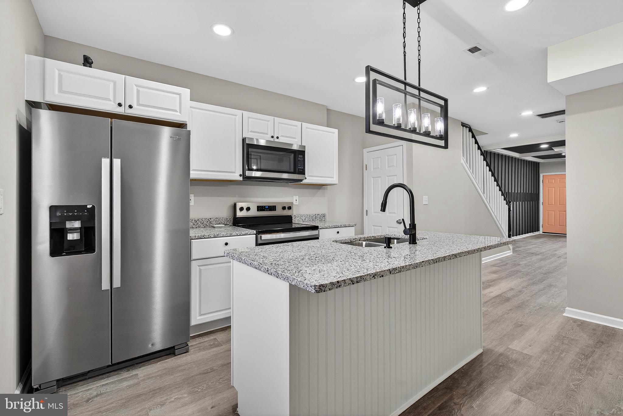 a kitchen with stainless steel appliances granite countertop a refrigerator a sink a stove a microwave and island