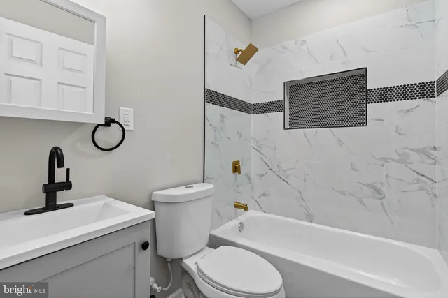 a bathroom with a granite countertop toilet sink and mirror