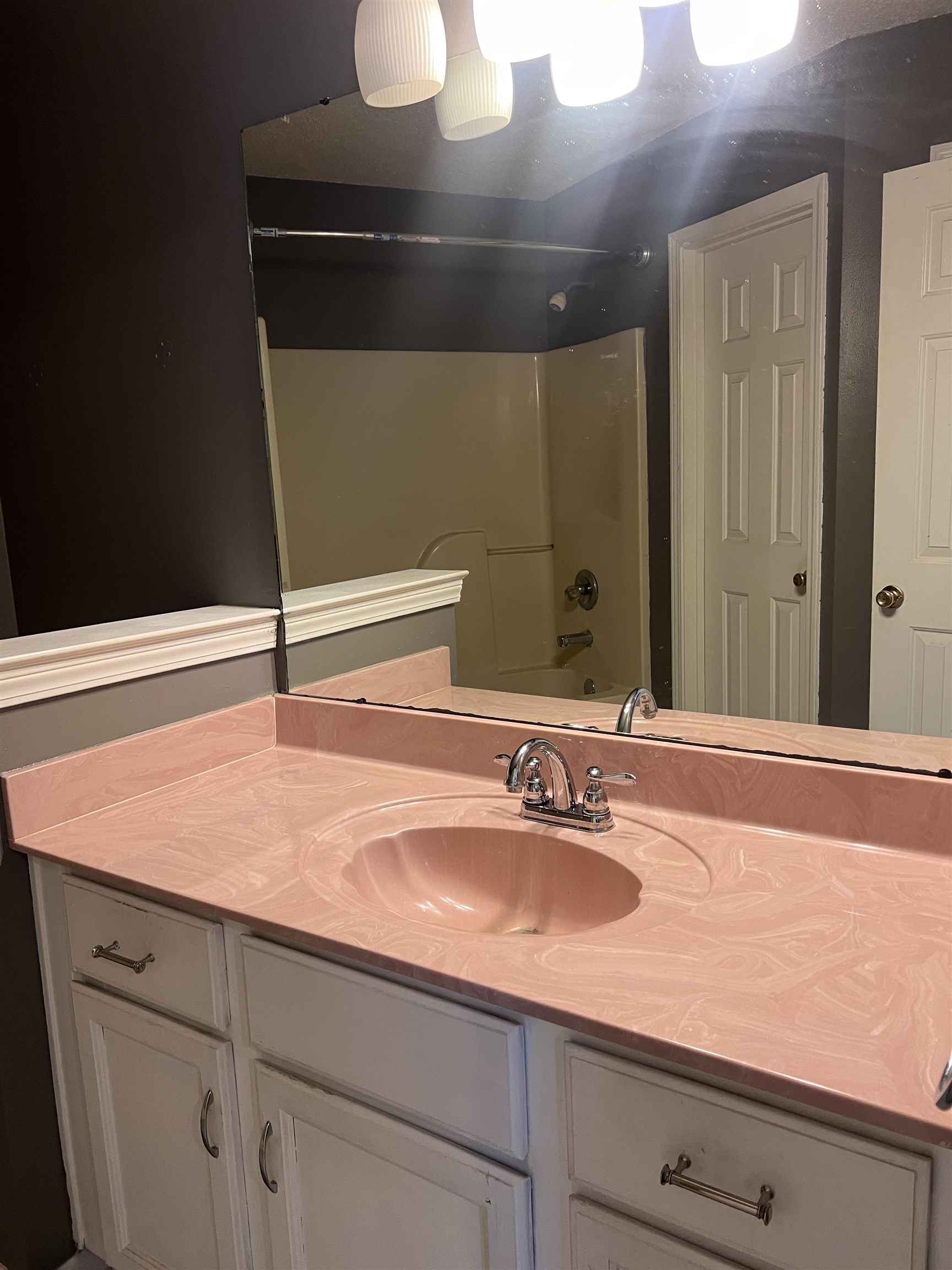4005 Long Creek Road Memphis, TN 38125 - Photo 30 of 36 Vanity with a pink countertop and integrated shell-shaped sink, chrome faucet, white cabinetry, and wall-mounted light fixture