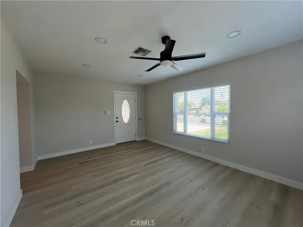 a view of an empty room with wooden floor and a window