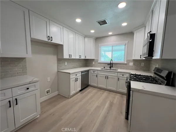 a kitchen with granite countertop white cabinets stainless steel appliances a sink and a window