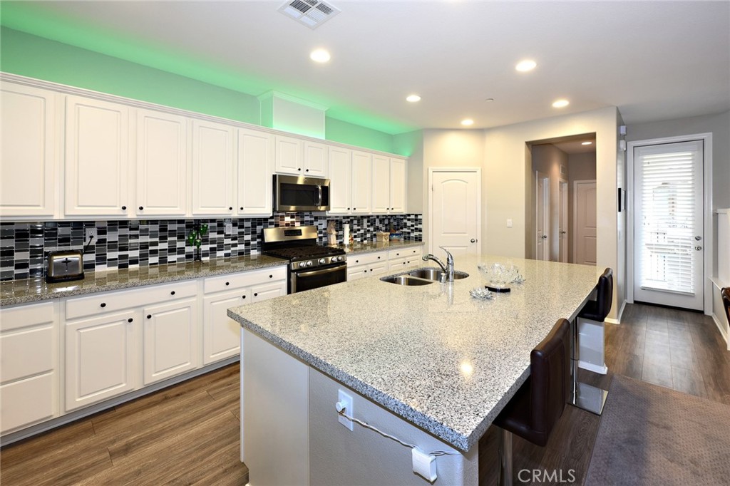 443 Stratus Lane, Unit 4 Simi Valley, CA 93065 - Photo 14 of 32 a kitchen with granite countertop a sink a center island stainless steel appliances and cabinets