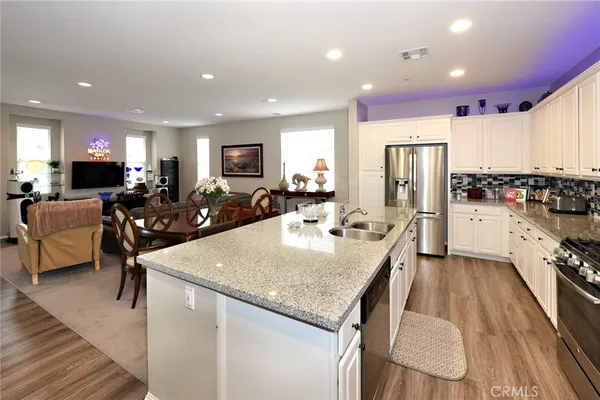 a large kitchen with sink a refrigerator and chairs