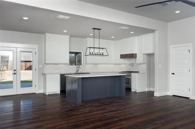 a kitchen with granite countertop a stove a sink and a refrigerator