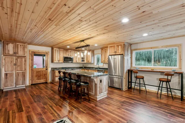 a kitchen with stainless steel appliances granite countertop a stove refrigerator dining table and chairs with wooden floor