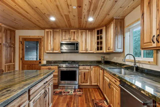 a kitchen with stainless steel appliances granite countertop a sink stove and cabinets