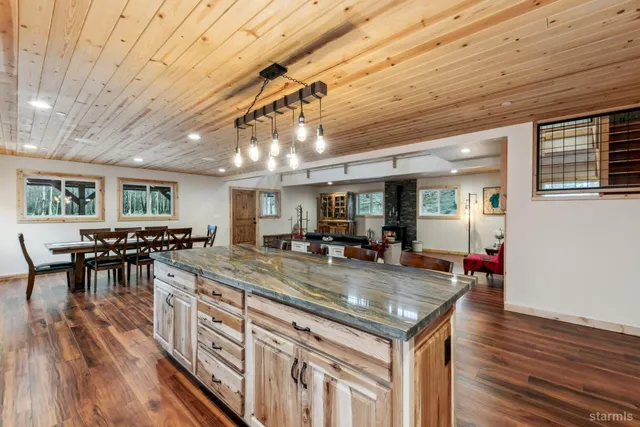 a kitchen with stainless steel appliances granite countertop a stove a refrigerator a dining table and chairs with wooden floor