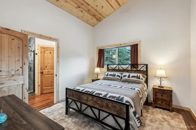 a bedroom with a bed a table and wooden floor