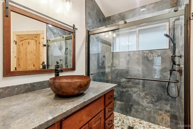a bathroom with a granite countertop sink a mirror and a shower