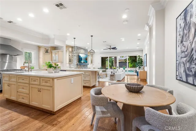 a kitchen with stainless steel appliances kitchen island granite countertop a sink a stove a dining table and chairs
