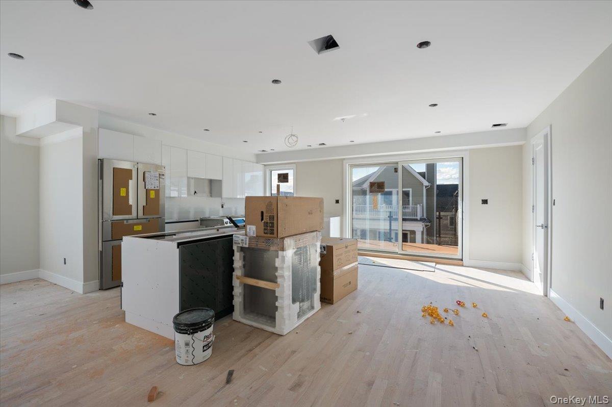 56 Oregon Street Long Beach, NY 11561 - Photo 5 of 25 Kitchen featuring white cabinetry, freestanding refrigerator, light wood-style floors, a center island, and modern cabinets