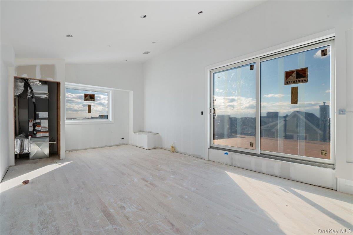 56 Oregon Street Long Beach, NY 11561 - Photo 9 of 25 Unfurnished living room with wood finished floors, lofted ceiling, and heating unit