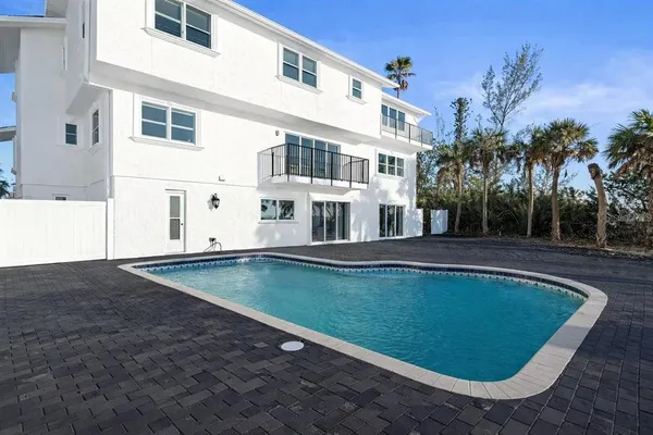 a view of pool with lawn chairs and plants