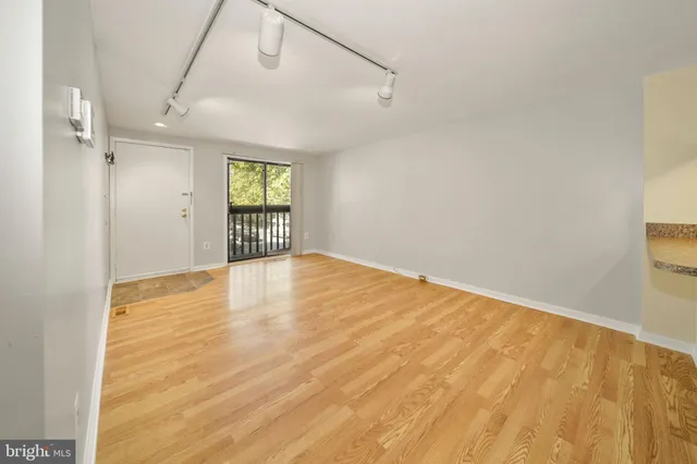 a view of an empty room with wooden floor and a window