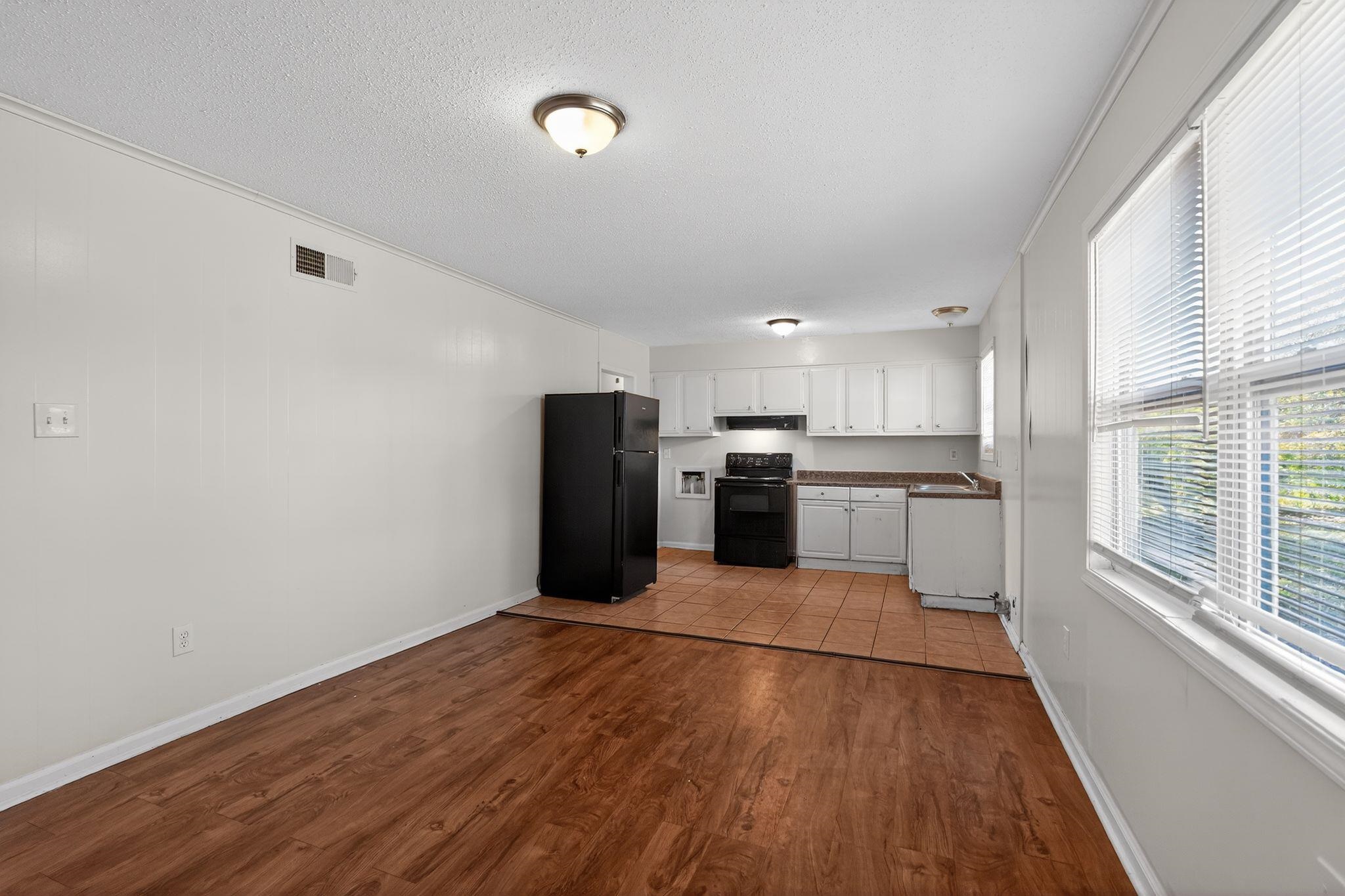 3637 Neely Road Memphis, TN 38109 - Photo 11 of 30 Kitchen with black appliances, white cabinets, dark countertops, dark wood finished floors, and a textured ceiling
