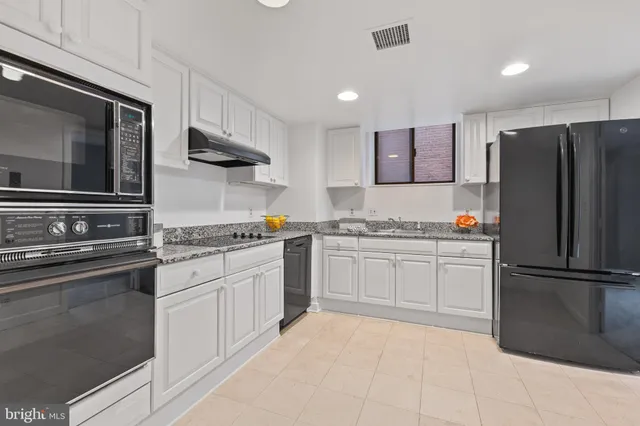 a kitchen with granite countertop white cabinets and stainless steel appliances