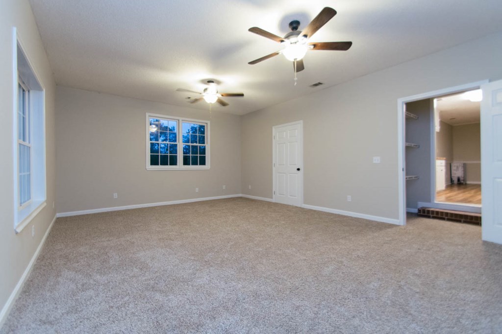 4841 Sandy Point Road Lizella, GA 31052 - Photo 18 of 42 an empty room with windows and fan chandelier fan