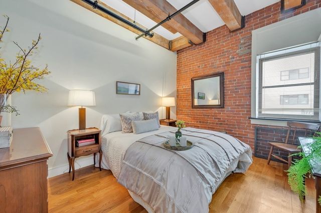 a bedroom with a bed and a potted plant on the dresser