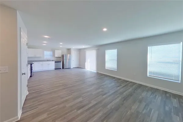 a view of empty room with a kitchen and a window