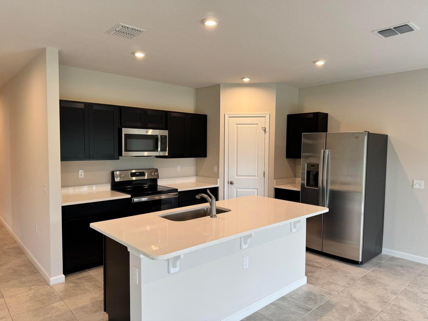 345 Clementine Road Fort Pierce, FL 34981 - Photo 12 of 13 a kitchen with stainless steel appliances a refrigerator sink and microwave