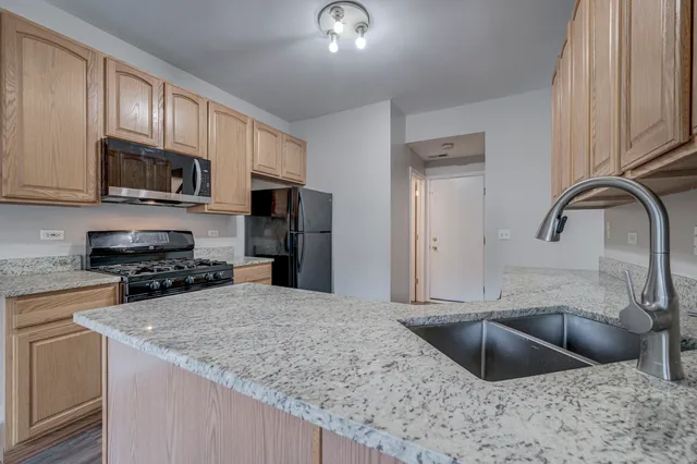 a kitchen with stainless steel appliances granite countertop a sink a microwave and refrigerator