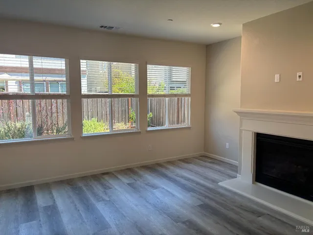 an empty room with wooden floor and fireplace