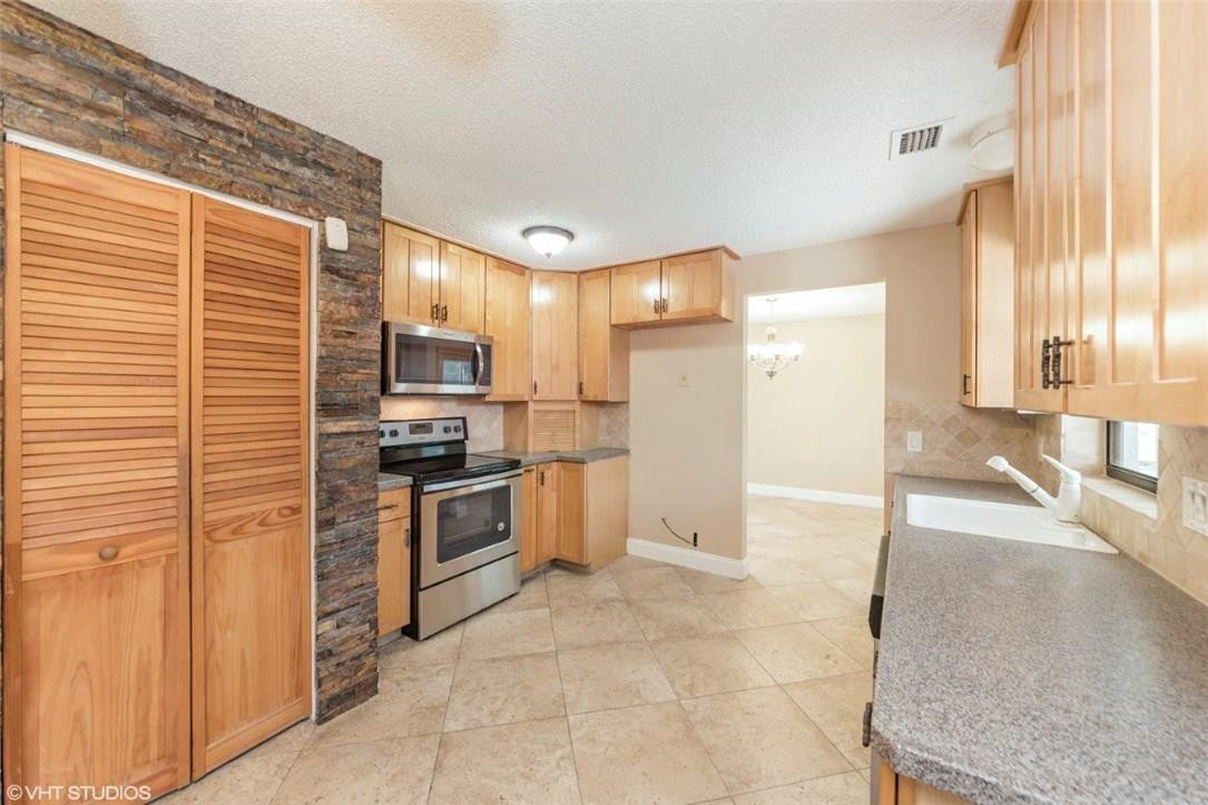 22494 Grouper Court Boca Raton, FL 33428 - Photo 6 of 22 a kitchen with granite countertop a stove a sink and a refrigerator