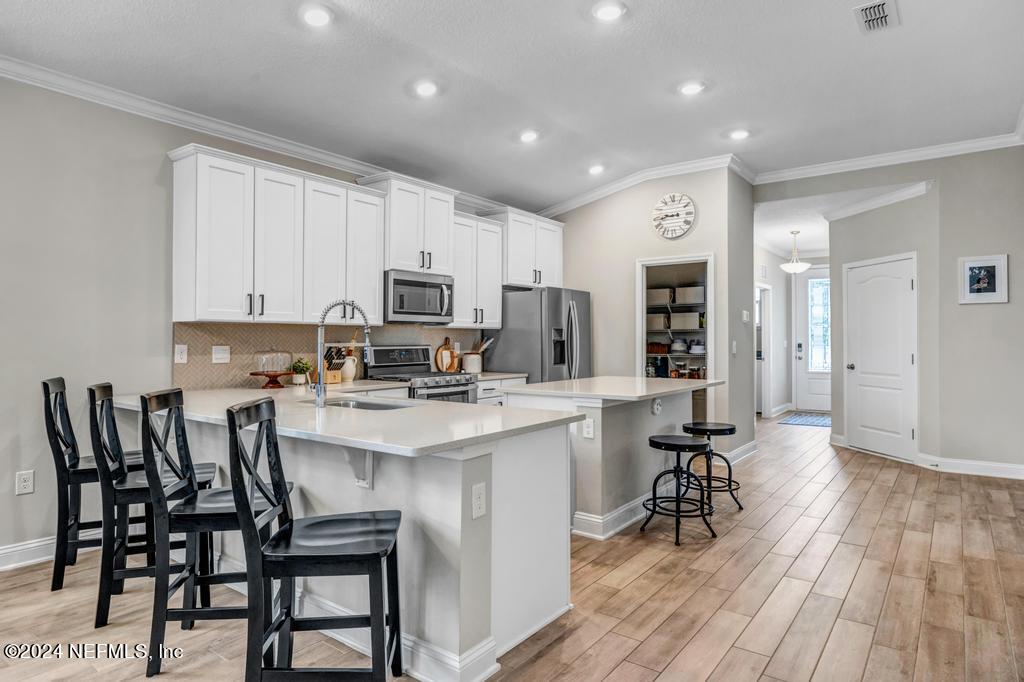 196 Creekmore Drive St. Augustine, FL 32092 - Photo 6 of 51 a kitchen with a dining table chairs refrigerator and cabinets