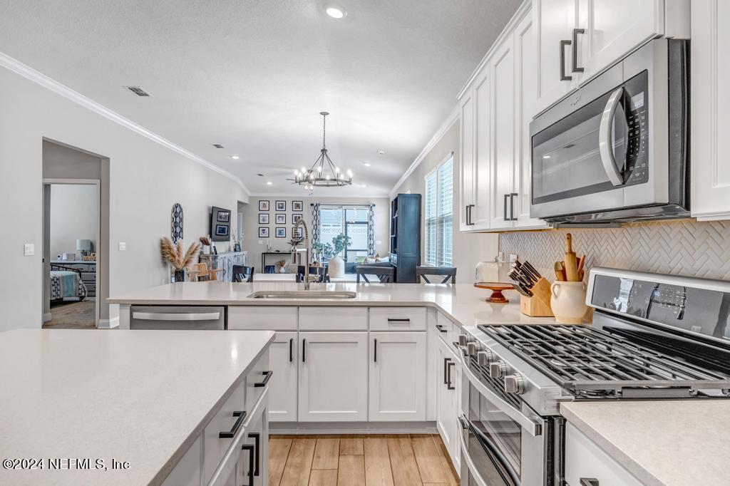 196 Creekmore Drive St. Augustine, FL 32092 - Photo 9 of 51 a kitchen with stainless steel appliances a white stove top oven and a chandelier